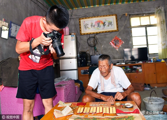 董海生(左)在拍摄娄柱祥老人当年的证书和奖章.图片