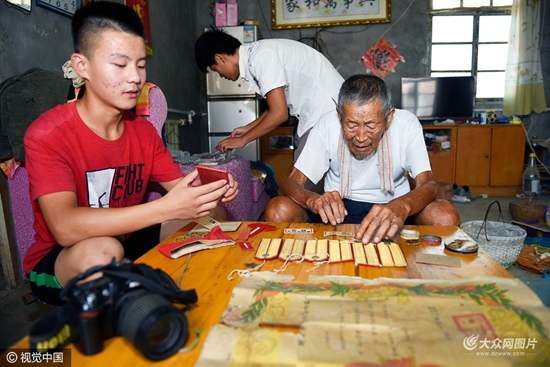 董海生(左)在拍摄娄柱祥老人当年的证书和奖章.图片